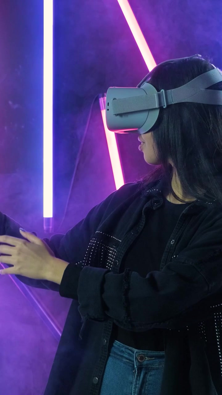 Giovane Donna che Utilizza un Visore per la Realtà Virtuale in uno Studio Illuminato al Neon