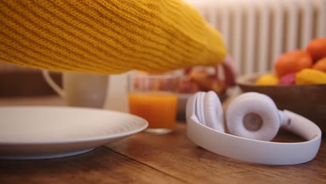 Dolly-wide-shot-of-a-table-set-for-breakfast-with-a-pair-of-white-headphones-on-one-side