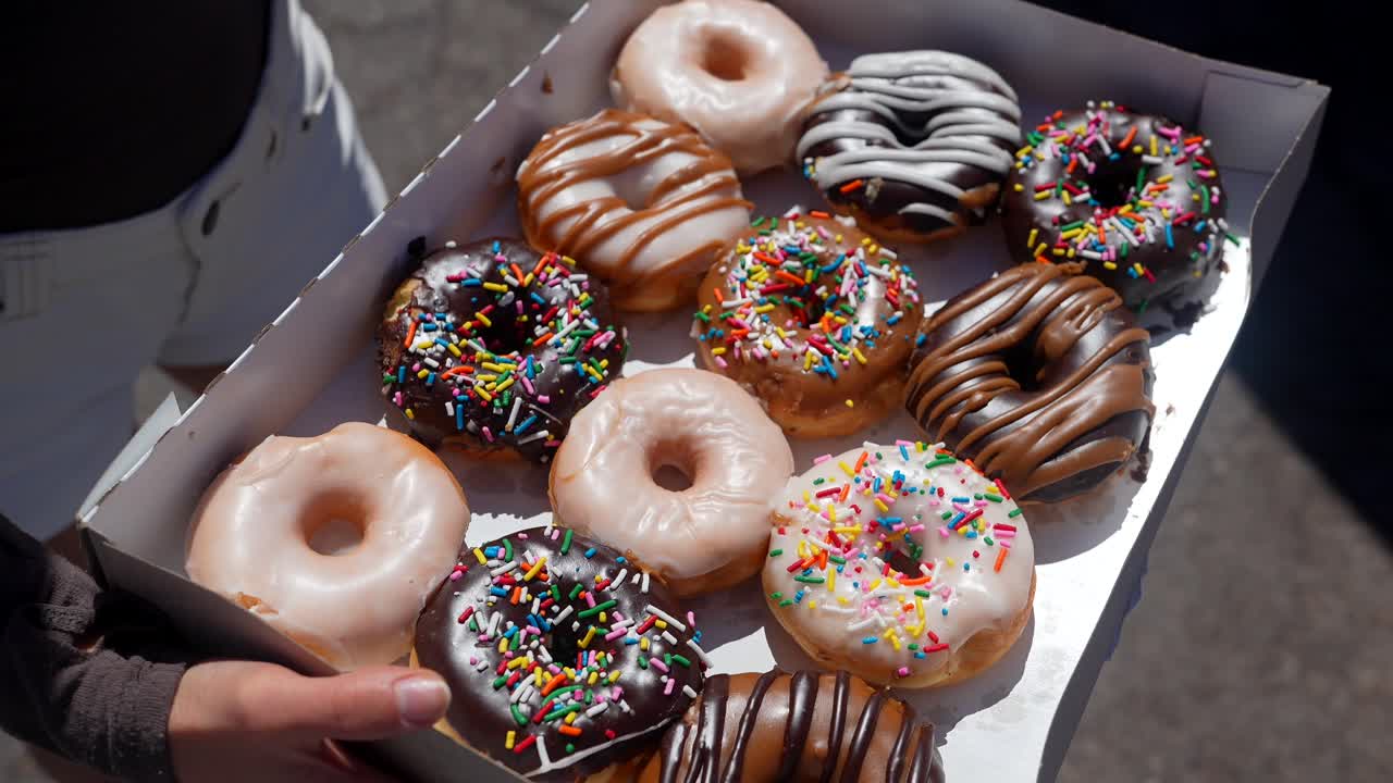 Mãos Segurando uma Caixa de Deliciosos Donuts Variados