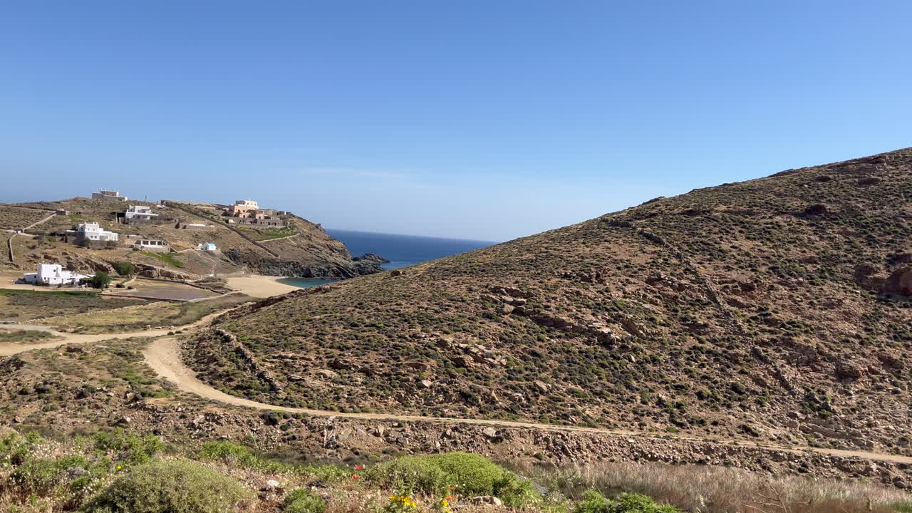 A scenic drive on a dirt road reveals a tranquil beach as the view opens from behind a rugged hillside. Perfect for destination promos, travel vlogs, digital detox, and travel documentary projects