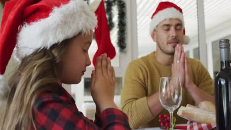 focused caucasian daughter and father praying together before christmas dinner