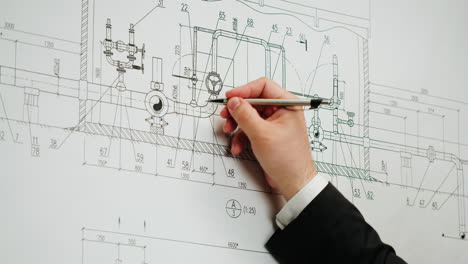 a hand working on a technical engineering blueprint