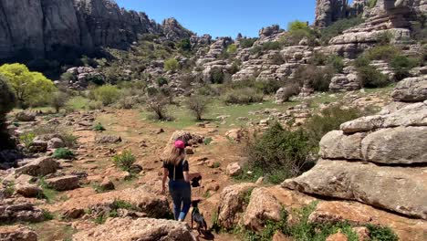 mujer joven rubia con gorra paseando a su perro en el parque natural de el torcal de españa