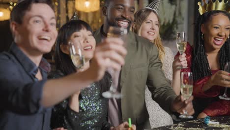 tracking shot of friends raising their glasses and saying happy new year