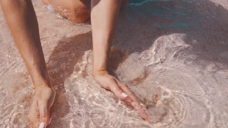 woman hands scooping pink sand on the beach