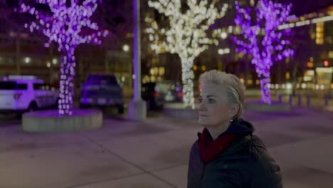 senior woman walking alone in a city at nighttime during the christmas season