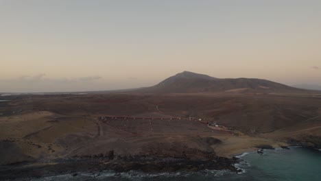 Landscape-of-Papagayo-beach-in-Lanzarote-with-brown-sand-and-rugged-cliffs-backdropped-by-mountain