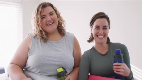 Retrato-De-Una-Pareja-De-Lesbianas-Caucásicas-Manteniéndose-En-Forma-Y-Sosteniendo-Botellas-De-Agua