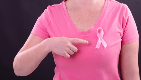 video of midsection of caucasian woman wearing pink cancer awareness ribbon on black background