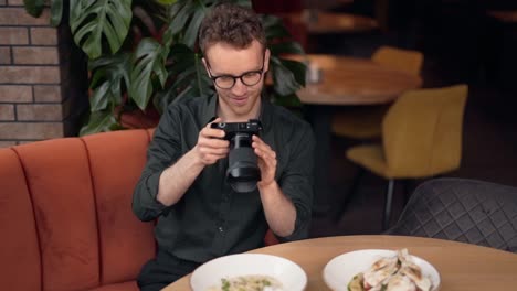 un joven apuesto toma fotos de platos en un café