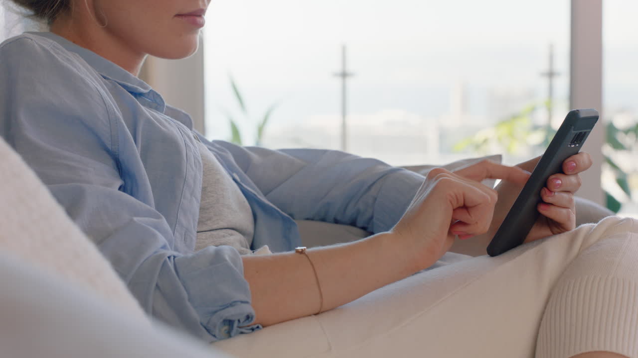 beautiful young woman using smartphone relaxing on couch at home browsing online texting enjoying sharing comfortable lifestyle on social media