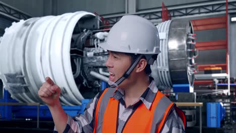close up side view of angry asian male engineer with safety helmet shouting at someone while standing with airplane engine maintenance conducted, analytics checking the turbine