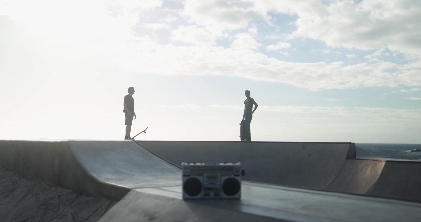 Silhouetted Young Men with Skateboards and Boombox at Skatepark