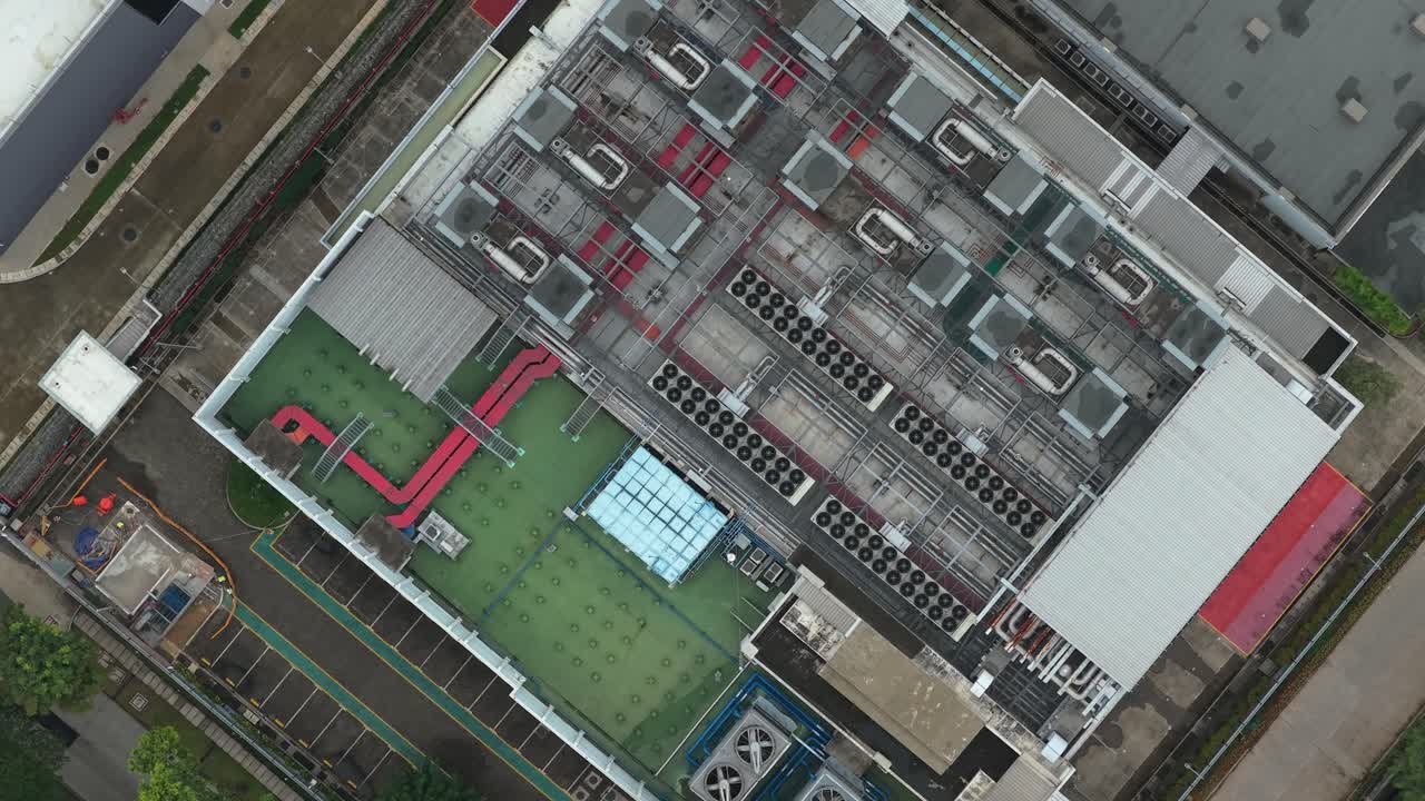 Top-down luftfoto, der langsomt roterer over taget af en stor datacenterbygning, og som viser dets komplekse køle- og ventilationssystem