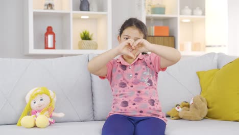 Niña-Haciendo-Símbolo-De-Corazón-Para-Cámara.