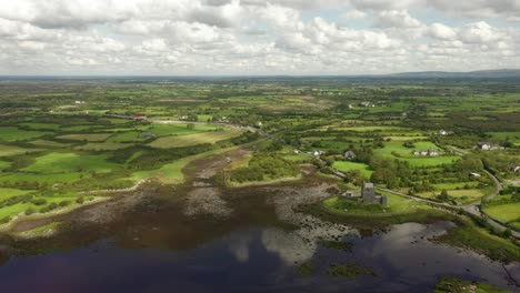 dunguaire castle, kinvara, galway, ireland, august 2020, drone slowly pulling backwards across coastal waters and rural landscape