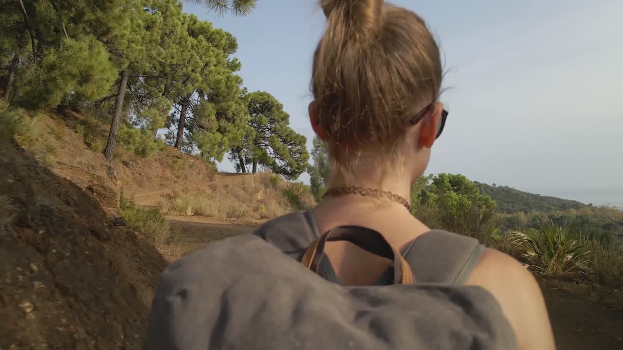 únete a nosotros en un viaje sereno mientras seguimos a una mujer por detrás, subiendo un pintoresco sendero de montaña