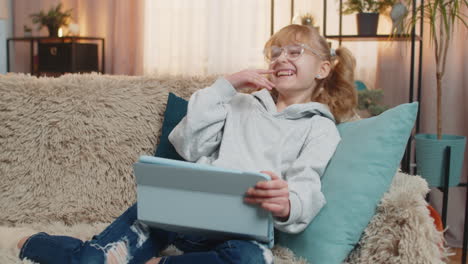 young teenager girl enjoys watching online cartoons on tablet screen at home giggling laughing