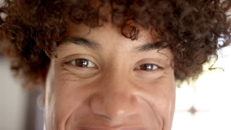 a close-up captures a young biracial man with a cheerful expression at home