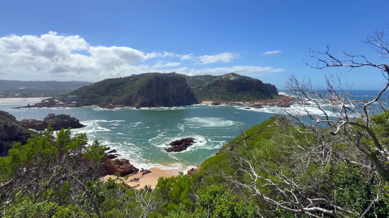 Panoramica a destra del paesaggio costiero della laguna di Knysna con scogliere rocciose e acque blu. Sudafrica.