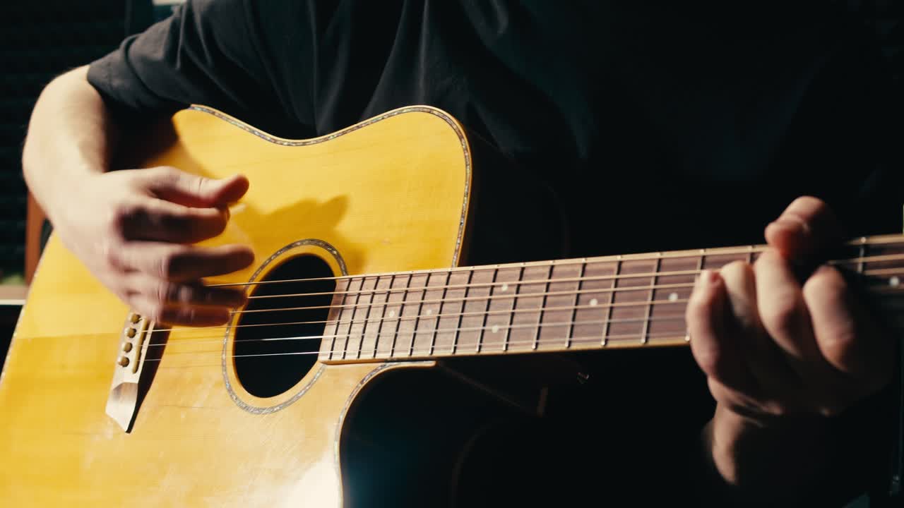 joven músico comprobando las cuerdas de una guitarra acústica de cerca. guitarrista masculino afinando el sonido de un instrumento musical.