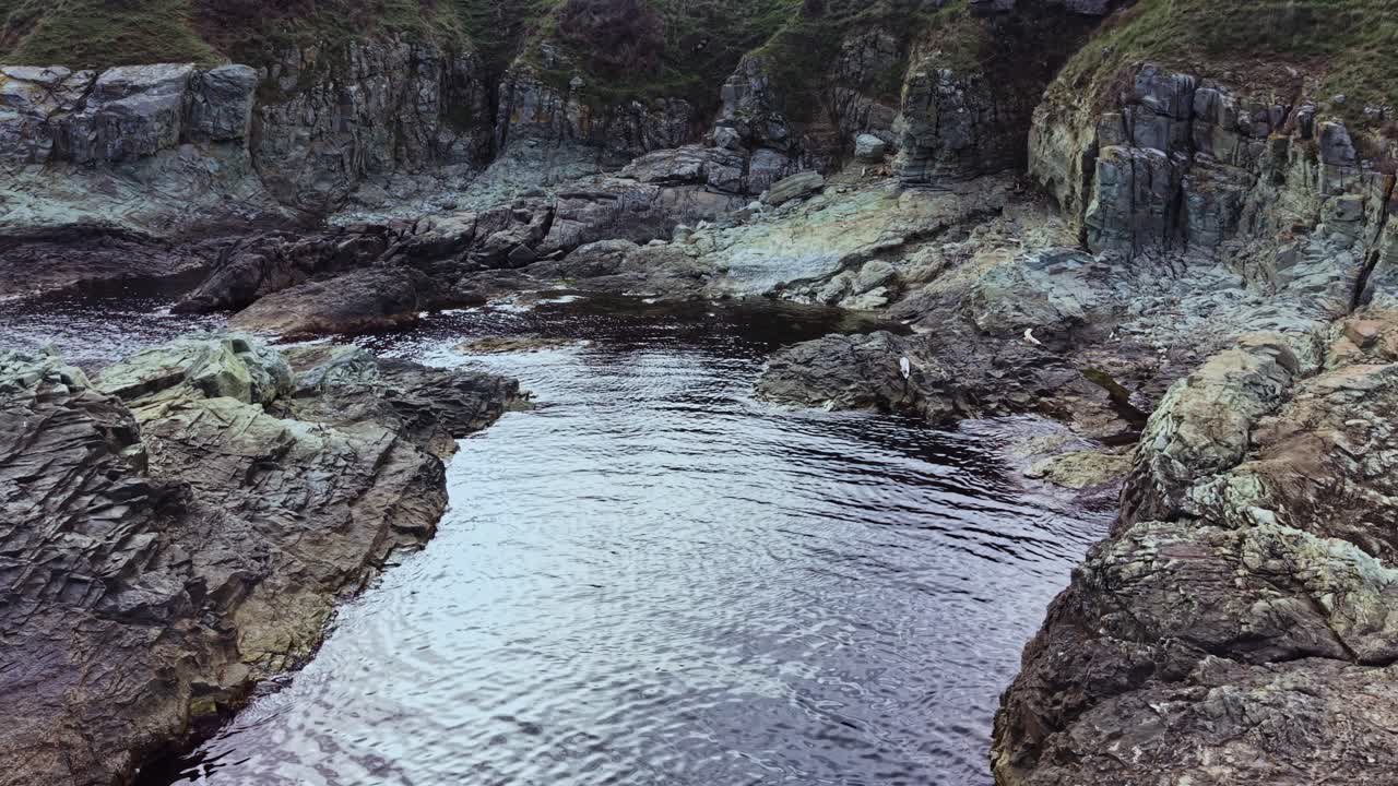 Stunning aerial view of rocky coastline with calm waters at sunset