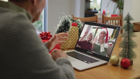 Caucasian-senior-man-having-christmas-video-call-on-laptop-with-son-and-grandson-on-screen