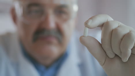 doctor holds a pill in his hands and looks at the camera close-up. high quality 4k footage