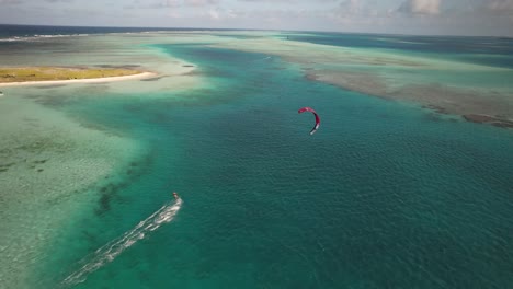 Vista-Aérea-De-Un-Surfista-De-Cometas-Rojas-En-Un-Mar-Turquesa,-Día-Soleado,-Ambiente-Tropical,-Desde-Arriba