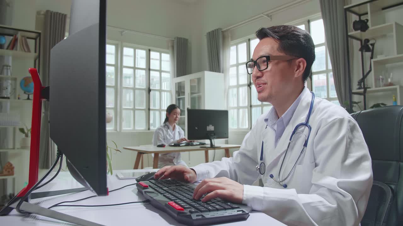 Asian Male Doctor Communicates With Patient By Video Link, Doctor Consults Patient Using Modern Technologies, Using Desktop Computer In Workplace