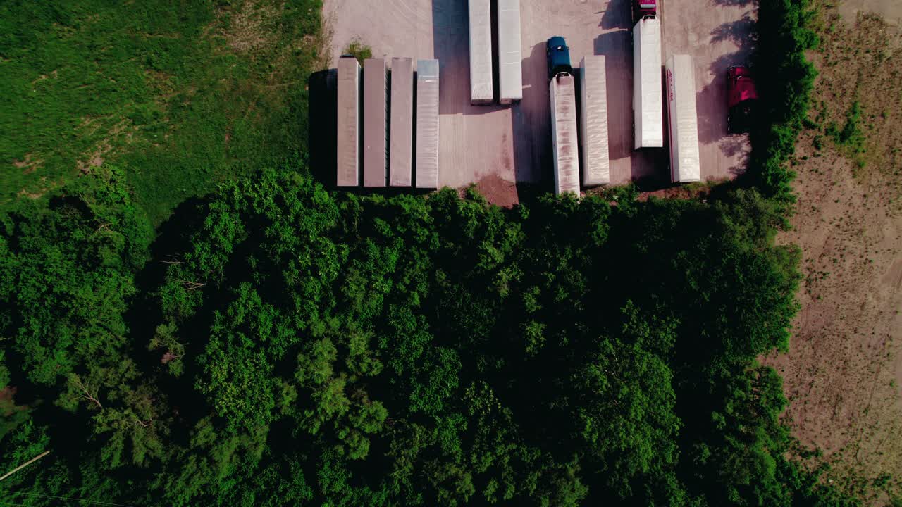 미국 물류 인프라를 보여주는 숲의 가장자리에 주차된 건조한 밴과 냉장 트레일러가있는 반 트럭의 거친 주차장