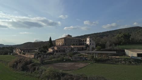 Ascending-drone-shot-on-a-typical-farm-in-Catalonia,-Spain,-surrounded-by-fields,-daylight