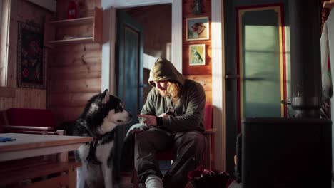 the man is petting his dog while enjoying a drink during winter in bessaker, trondelag county, norway - static shot