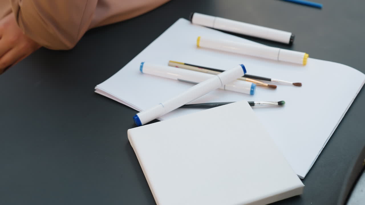 정확한 모서리 위치 지정 기술, 백인 예술가가 테이블 위에 종이를 정확하게 배열하고, Designer가 꼼꼼하게 시트 모서리를 조정하여 정확한 배치와 깔끔한 레이아웃으로 구도를 연출합니다.