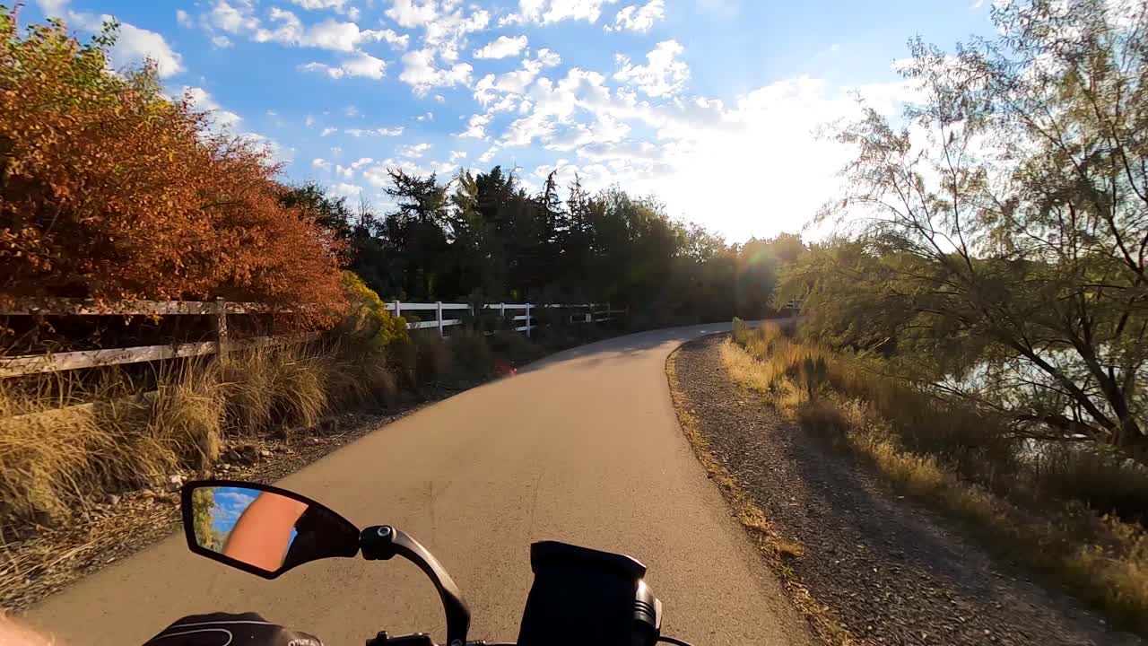 Riding a bicycle along a trail by the river - sky reflecting off the water on sunny morning
