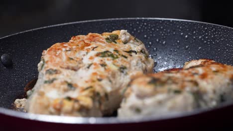 Pechugas-De-Pollo-Al-Vapor-Cocinadas-En-Una-Sartén-Cubierta-De-Aceite-Burbujeante-Que-Cubre-La-Comida-De-La-Cena-Con-Una-Textura-Crujiente-Y-Sazonada-Con-Romero,-Primer-Plano-De-La-Comida