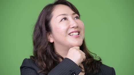 mature happy beautiful asian businesswoman smiling while thinking