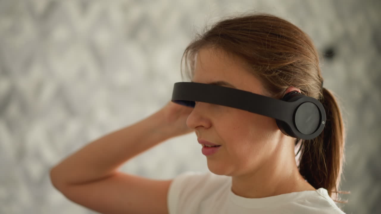 mujer oculta los ojos usando auriculares banda para la cabeza corriendo en la residencia. mujer activa disfruta de auriculares mientras hace ejercicio en la cinta de correr en el gimnasio. entrenamiento divertido