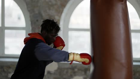 male boxer training at boxing studio in gloves, punching pear