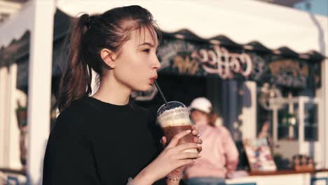 teen girl drinking iced coffee outside a cafe