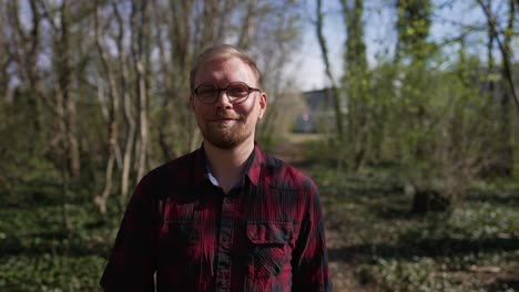 confident, smiling man walks towards camera, sunny day in forest, tracking shot