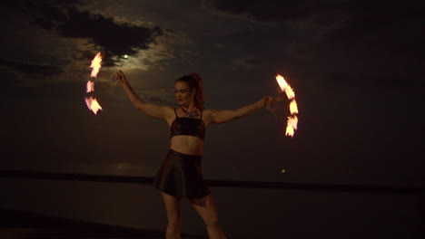 mujer girando con ventiladores de fuego giratorios en la playa a orillas del lago, cámara lenta exterior nocturna