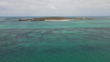 toma aérea acercándose a una isla desierta en un océano de agua turquesa durante la luz del sol