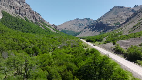 vuelo aéreo sobre los árboles en el suelo del valle al lado de la carretera con un coche que pasa por chile