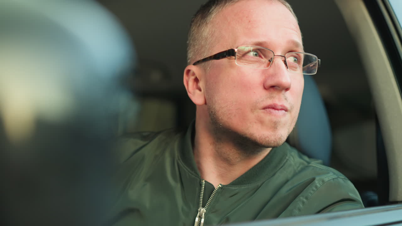 스티어링 에 손을 고 있는 남자와 녹색 재을 입은 남자의 클로즈업, 집중과 기대의 순간, 아마도 창밖으로 집중적으로 쳐다보는