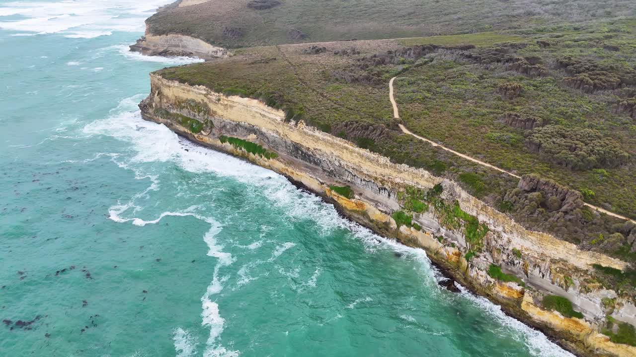 Aerial footage of Port Campbell's rugged coastline with turquoise waters and dramatic cliffs under soft daylight
