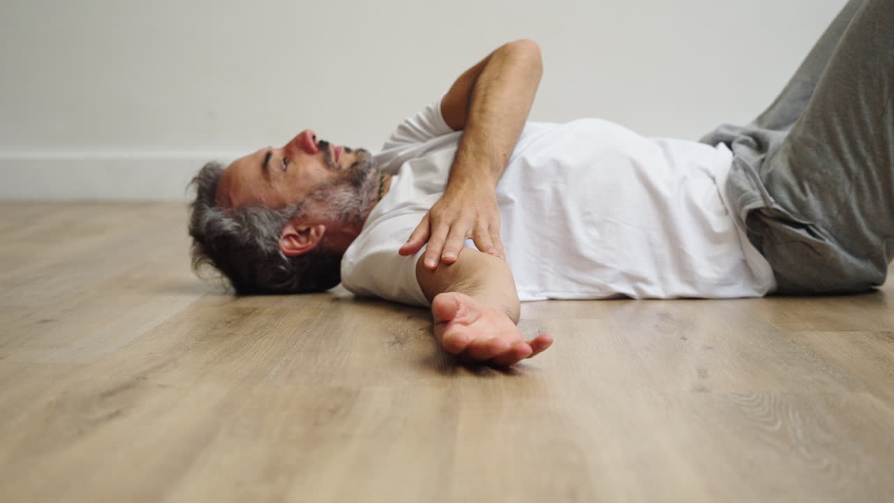 Adult Man Lying on Floor Experiencing Pain or Medical Emergency