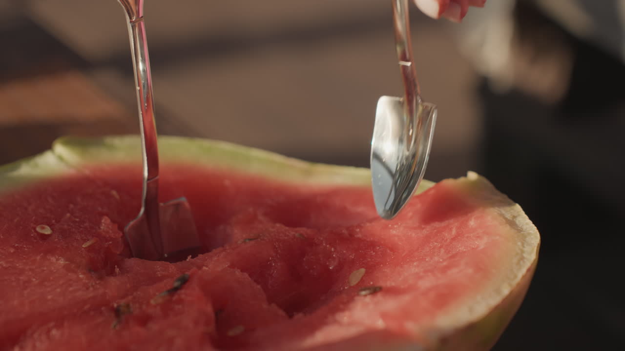 CloseUp White Woman Spoon Scooping Ripe Watermelon Half, Bright Red Flesh, Seeds And Juice Glisten Under Warm Sunlight On Patio, Elegant Manicure Holds Spoon While Flesh Lifts In Fresh Summer