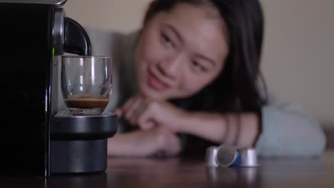 cosecha mujer asiática contemplando la cápsula máquina de café preparando bebida caliente