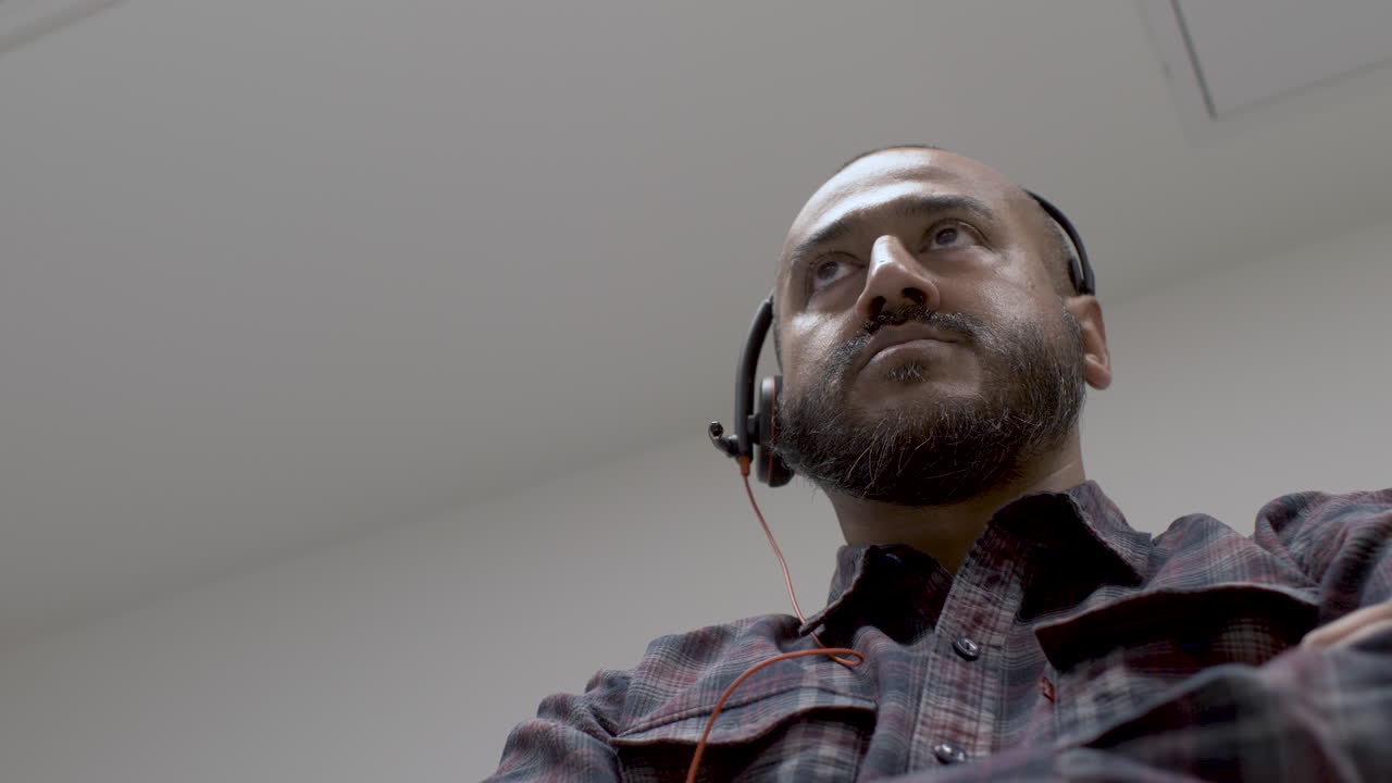 comerciante diurno de minorías étnicas con auriculares y asintiendo suavemente con la cabeza mirando hacia adelante